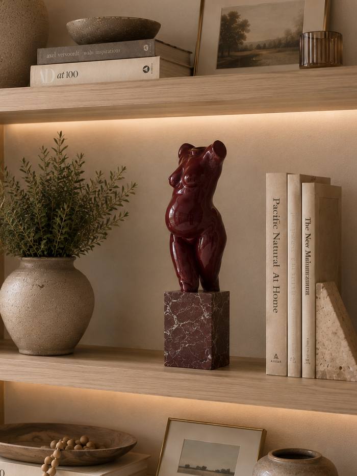 A commissioned torso sculpture in oxblood lacquer on a red marble plinth, on a carved stone mantel.