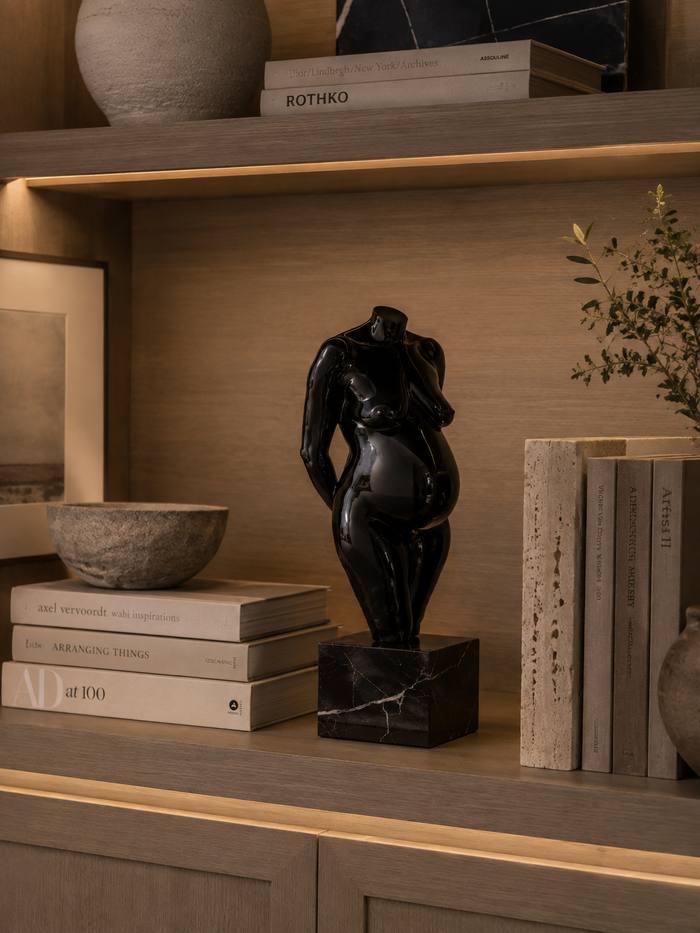 A commissioned sculpture in piano black lacquer on a black marble plinth, on a lit oak shelf.